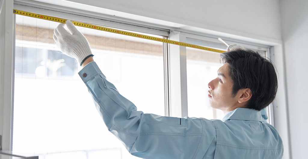 Persona midiendo el hueco de una ventana con cinta métrica grande
